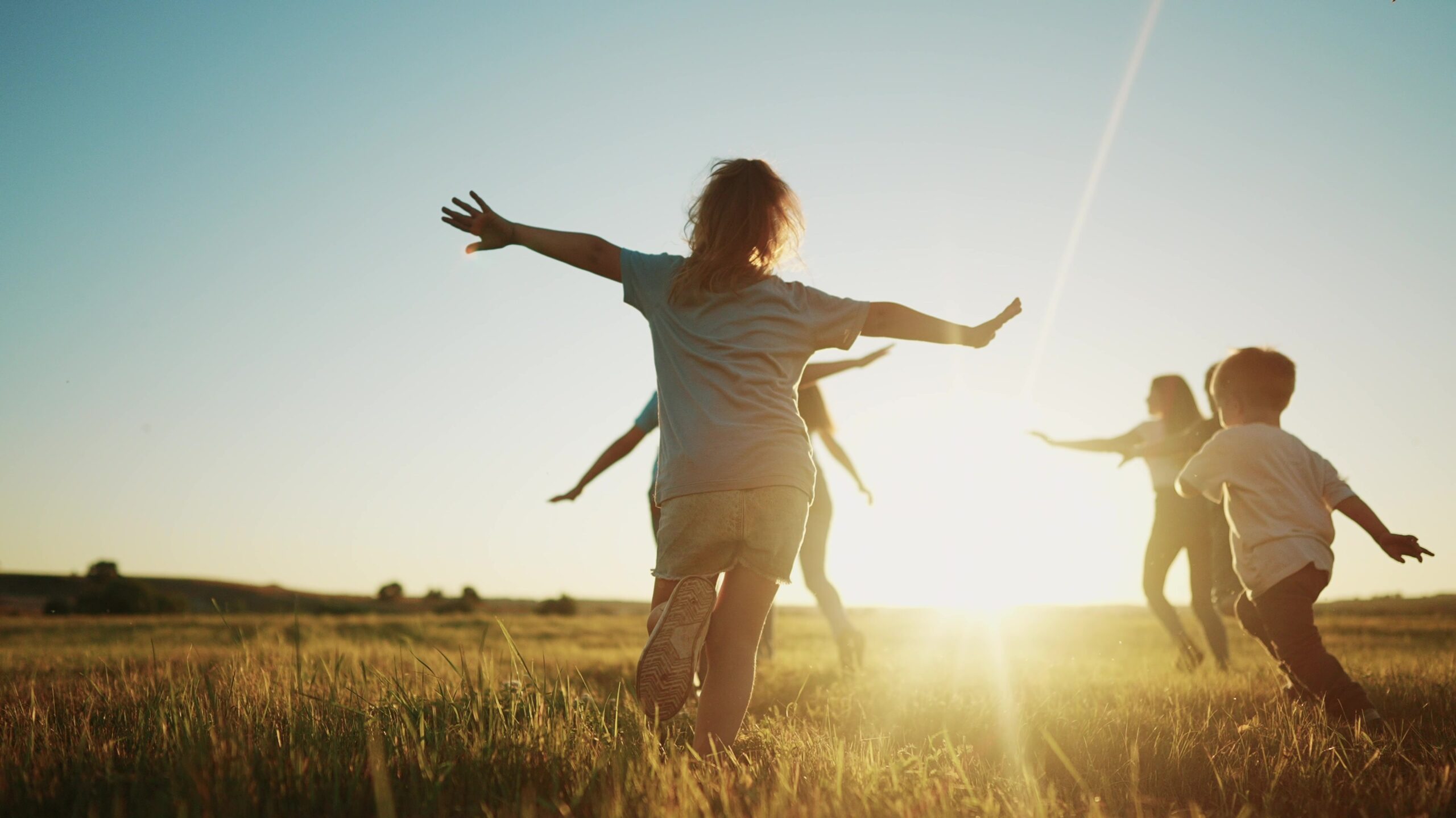 Gesundheit & Nachhaltigkeit / Health & Sustainability: Kinder laufen über eine Wiese im Sonnenuntergang, dies soll an Reflexion, Fokus auf das Wesentliche sowie einen achtsamen Umgang mit sich selbst und der Umwelt erinnern.